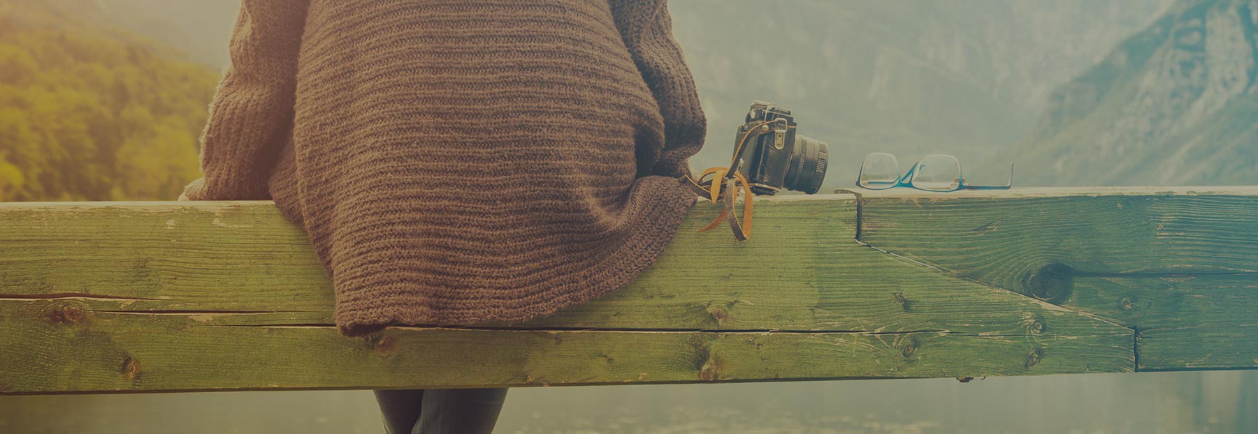 Close up of a woman sitting on a stack of wood by the water