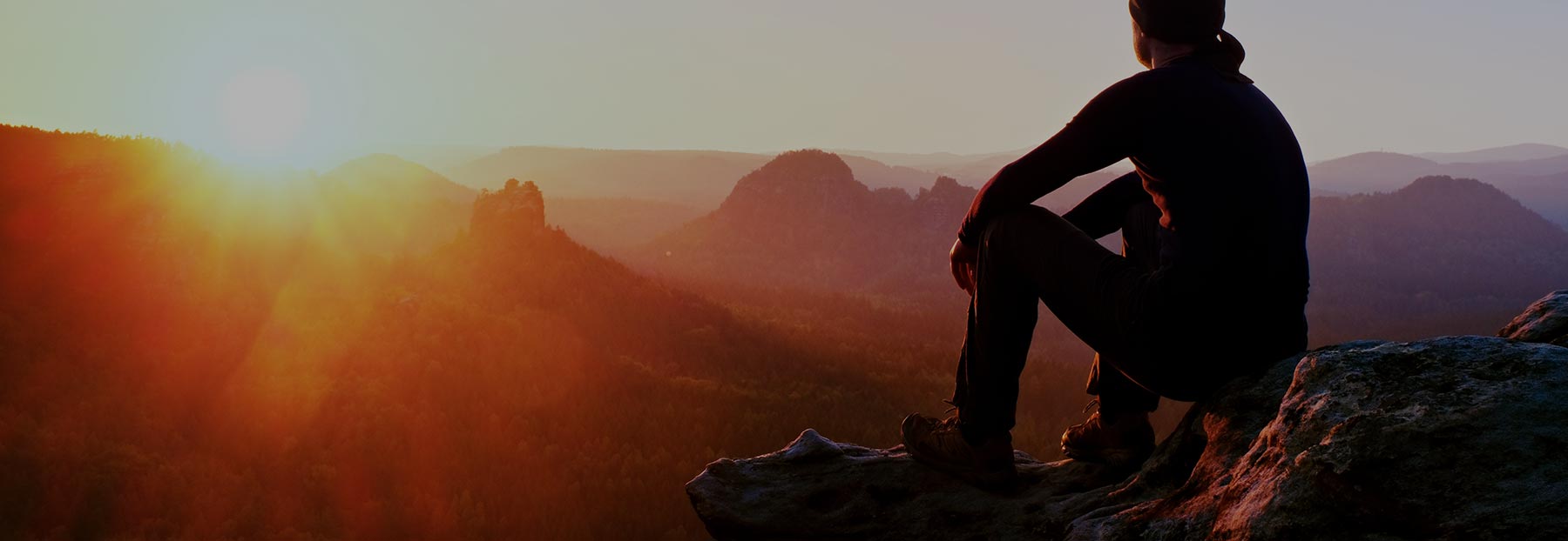Hiker sitting on mountain and watching the sunset