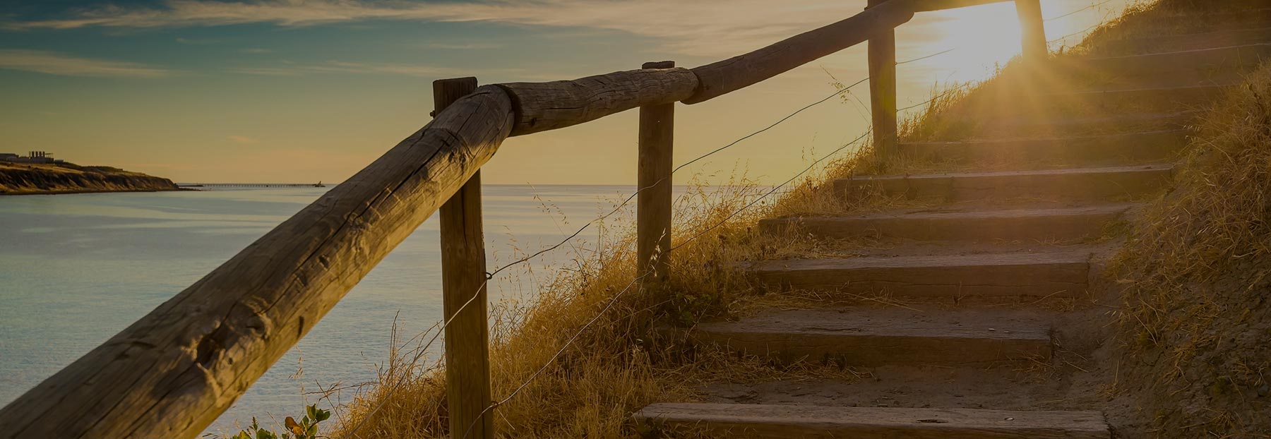 Close up of outdoor stairs along the edge of a cliff looking out into the ocean