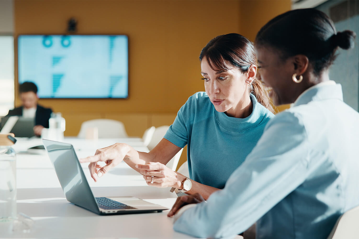 Two women collaborating on a laptop at a modern community workspace.