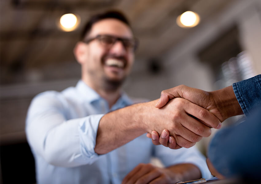 Two people shaking hands in a brightly lit communal space.