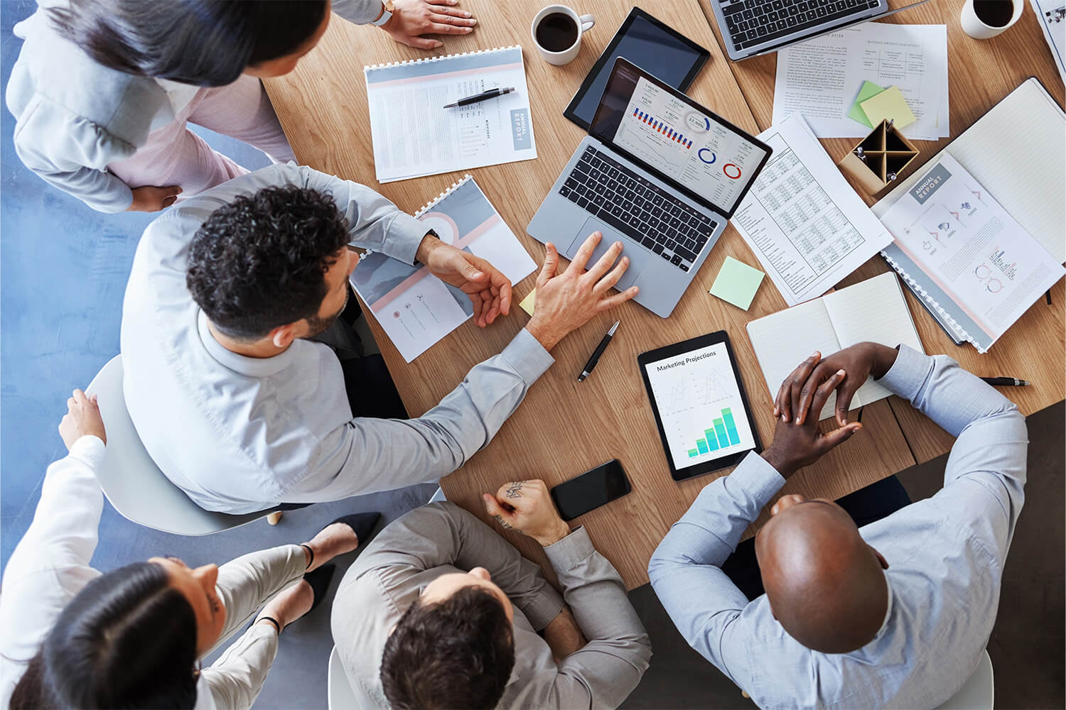 Group of professionals discussing investment plans at a table with laptops and documents.