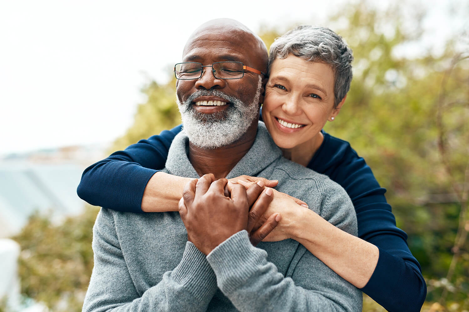 Happy senior couple embracing outdoors in a sunny green area.