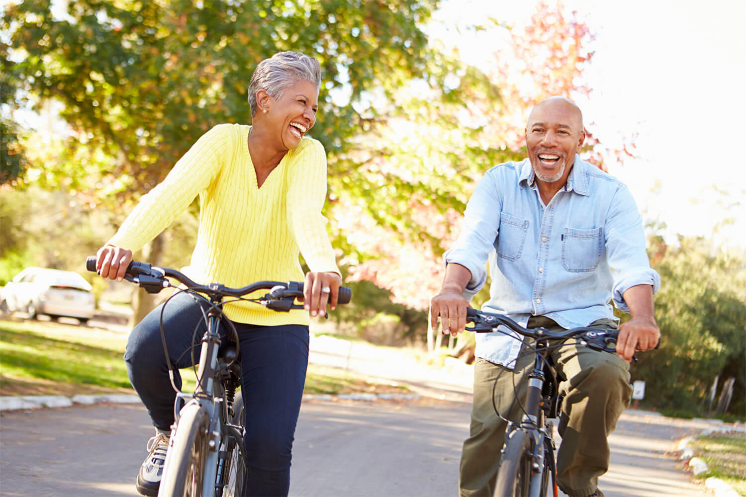Smiling senior couple biking outdoors on a sunny day.