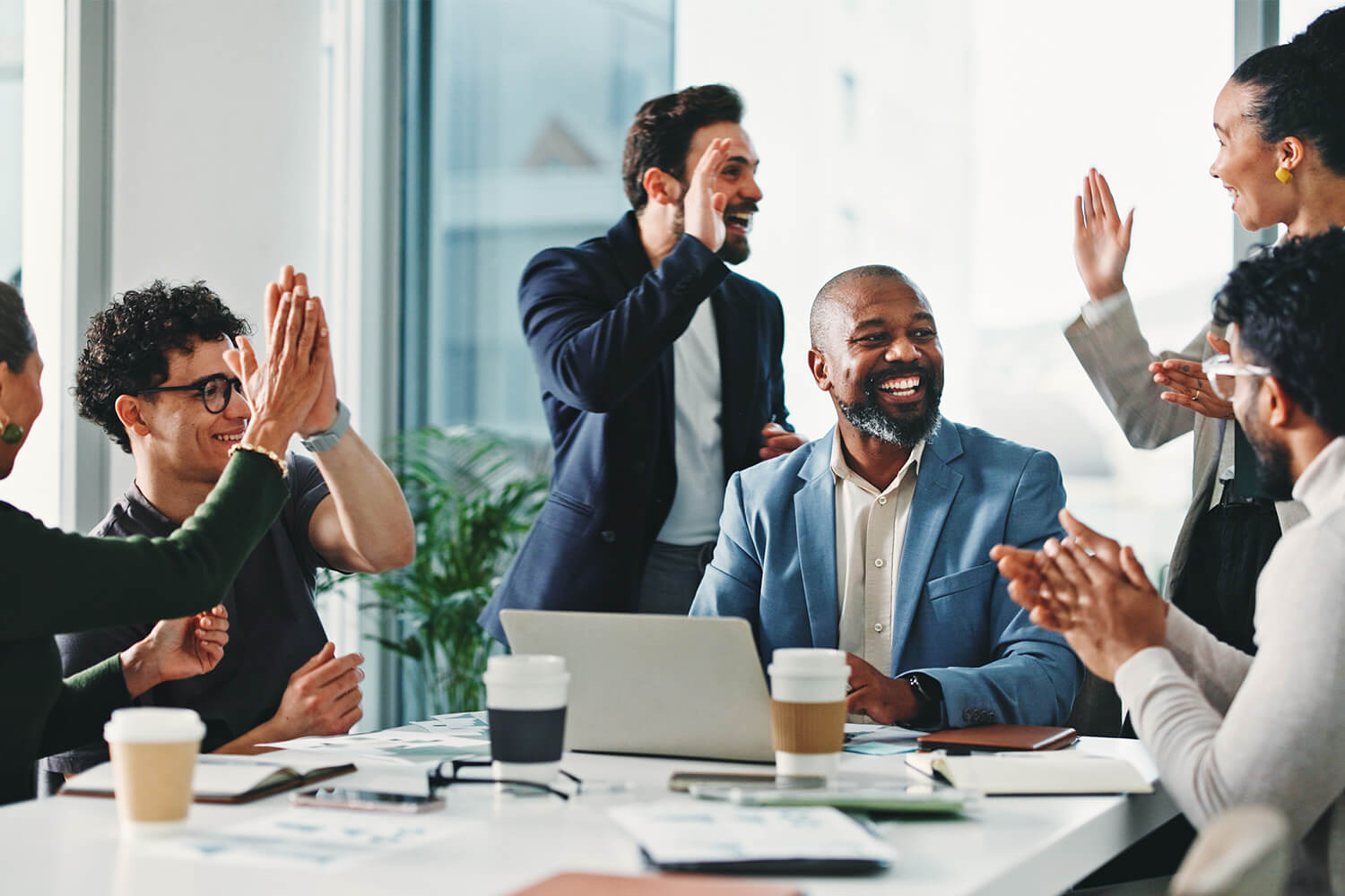 Diverse group of professionals celebrating success in a meeting room.
